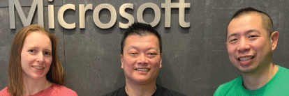 Three employees standing in front of Microsoft sign.